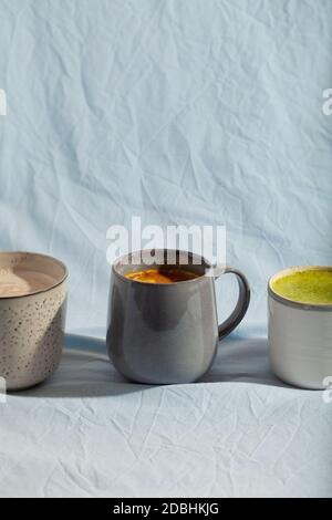 Veganes Kakao-Getränk mit Matcha, Kurkuma und Zimt auf blauem Hintergrund. Milchgetränk Stockfoto