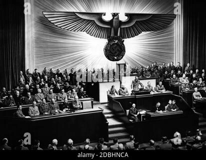 Adolf Hitler während seiner Rede über die Kriegserklärung an die USA. Links von Hitler sind Julius Schaub und Hans Heinrich Lammert, rechts Otto Dietrich und Albert Bormann. Über ihm, Reichstagspräsident Hermann Göring. Neben Hitlers freiem Sitz auf der Regierungsbank sind Joachim von Ribbentrop, Erich Raeder, Walther von Brauchitsch, Wilhelm Keitel, Wilhelm Frick und Joseph Goebbels. Auf der Bank oben, von rechts sitzend: Johann Ludwig Graf Scherin von Krosigk, Walther Funk, Walter Darre, Bernhard Rust, Hanns Kerrl, Hans Frank, Julius Dorpmueller, Arthur Seys Inquart und Fritz Todt. Stockfoto