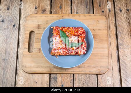 Gericht - Italienische Lasagne auf einem grauen Teller auf einem Holzhintergrund Stockfoto