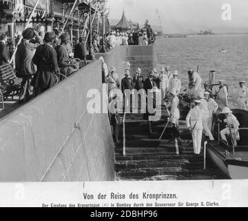 Kronprinz Wilhelm von Preußen war von November 1910 bis April 1911 auf einer Reise in die britische Kolonie in Indien. Hier, bei seiner Ankunft im Hafen von Mumbai (Bombay) Ende 1910, wo er vom Gouverneur von Mumbai, Sir George Sydenham Clarke, mit einem Handschlag (Mitte, Clarke in schwarzer Uniform und Wilhelm in weißer Uniform) begrüßt wird. Stockfoto