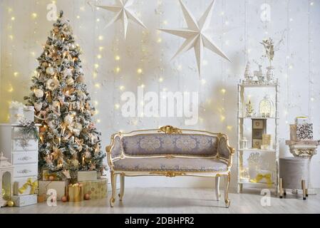 Stilvolle Weihnachtsdekorationen im Wohnzimmer mit klassischem Sofa, Weihnachtsbaum und Girlanden an der Wand Stockfoto