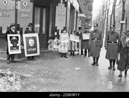 Doppelter Wachposten außerhalb einer Wahlstation. Die Anhänger von Düsterberg, Hitler, Hindenburg und Thaelmann stehen vor einem Wahllokal und kämpfen mit Wahlplakaten. Stockfoto