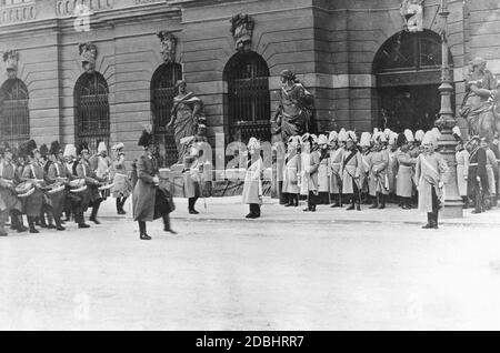 "Vorgeschichte des Ehrengardes vor Kaiser Wilhelm II. (Bildmitte, Begrüßung, mit Marschallstab in der Hand) nach der Paroleaugabe im Zeughaus. Rechts vom Kaiser befinden sich Generäle und Offiziere (in ihrer Mitte mit dunkler Schärpe: Adjutant General Hans von Plessen), und ein Admiral (rechts). Im Hintergrund ist der Eingang zum Zeughaus mit Statuen links und rechts.' Stockfoto