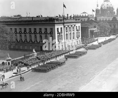 "Adolf Hitler steht auf einem Podium vor der Universität (links) und blickt auf die Parade der Soldaten des Linzer Hausregiments, Soldaten aus Österreich, das im März 1938 an Deutschland "annektiert" wurde. Die Militärparade am 20. April 1938 auf der Straße unter den Linden führt (von links nach rechts) an der Humboldt-Universität, der Gedenkstätte (heutige Neue Wache) und dem Zeughaus vorbei. Hinter ihnen befindet sich die Kuppel des Berliner Doms." Stockfoto