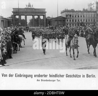 Bei einer Militärparade im September 1914 wurden vor dem Brandenburger Tor in Berlin gegnerische Geschütze präsentiert, die während des Krieges gefangen genommen wurden. Das Bild zeigt eine Menschenmenge, die die Parade einer Marschkapelle beobachtet. Zwei Offiziere reiten vorne. Stockfoto