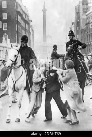 Polizisten nehmen einen Demonstrator in Londons Downing Street mit. Dort, vor dem offiziellen Wohnsitz des Premierministers, protestierten kommunistische Demonstranten. Eine Frau versucht, die Verhaftung zu verhindern. Stockfoto