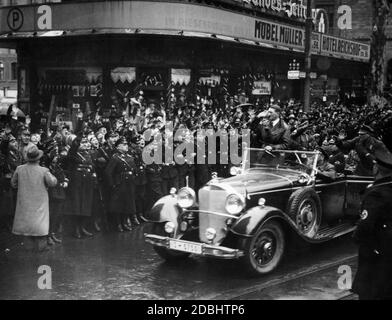 Adolf Hitler (hinter ihm Adjutant Julius Schaub) kommt nach dem erfolgreichen Referendum über die Annektierung der Saarregion an das Deutsche Reich vor dem Hotel Excelsior in Saarbrücken an. Er wird von einer begeisterten Menschenmenge begrüßt. Stockfoto