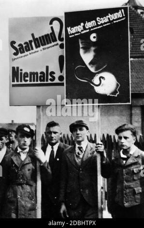 'Die Kommentatoren halten Plakate mit den Worten ''Saarbund? (Unabhängige Arbeiter- und Bürgerpartei) niemals!'' Und ''Kämpfe gegen den Saarbund!'' Die sich gegen saarländische Separatisten richten." Stockfoto