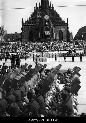 Adolf Hitler in einem Mercedes auf dem sogenannten Adolf-Hitler-Platz (im Hintergrund die Frauenkirche sowie die Tribüne) nimmt während des NSDAP-Kongresses in Nürnberg den Gruß des Reichsarbeitsdienstes ein. Links Wilhelm Frick. Stockfoto