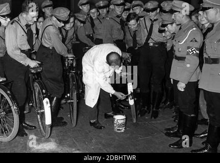 Um auf den Straßen prominenter zu werden, malte ein Mann weiße Linien auf die Kotflügel der Fahrräder des Motor HJ. Mehrere Mitglieder der Motor HJ Berlin beobachten ihn beim Malen. Stockfoto