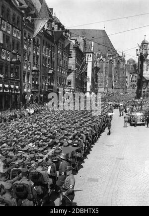 Blick auf die Formationen der SA während ihrer Parade auf dem sogenannten Adolf-Hitler-Platz beim NSDAP-Kongress in Nürnberg. Im Mercedes rechts grüßt Adolf Hitler. Im Hintergrund ist ein Teil der St. Sebaldus Kirche. Stockfoto