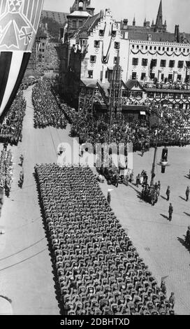 "Adolf Hitler, der in einem Mercedes steht, beobachtet den marsch der SA- und SS-Formationen auf dem sogenannten Adolf-Hitler-Platz während des NSDAP-Kongresses in Nürnberg. Hinter dem Auto steht der 'Schoene Brunnen'.' Stockfoto