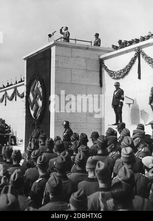 Adolf Hitler hält eine Rede von der Rotte des Zeppelinfeldes auf dem Reichsparteitagsgelände an die rund 54,000 Männer des Reichsarbeitsdienstes, die sich zur Parade versammelt haben. Hinter ihm steht Konstantin Hierl. Stockfoto