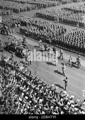 Adolf Hitler, der in einem Mercedes steht, fährt im Stadtstadion herum und begrüßt die Teilnehmer der Hitlerjugend bei ihrer Kundgebung während des NSDAP-Kongresses in Nürnberg. Auf dem Rücksitz links ist Baldur von Schirach, rechts Adjutant Wilhelm Brückner. Links unten befindet sich ein Musikorchester. Bei einer Trommler-Gruppe oben links gibt es zwei Sig Runen. Stockfoto