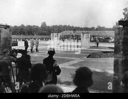 Während des NSDAP-Kongresses in Nürnberg (v.l.) gedenken Heinrich Himmler, Adolf Hitler und Viktor Lutze zusammen mit in der Luitpoldarena versammelten Formationen der Gefallenen der Bierhalle Putsch vor der von Fritz Mayer entworfenen Ehrenhalle für die Gefallenen des Ersten Weltkriegs. Links und rechts sind Kamerateams. Stockfoto