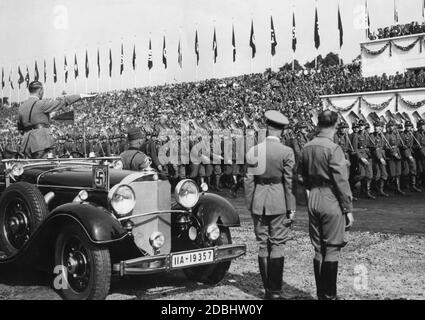 In einem Mercedes 770 K nimmt Adolf Hitler den Gruß des Reichsarbeitsdienstes auf dem Zeppelin-Feld. Vor ihm steht Konstantin Hierl. Stockfoto
