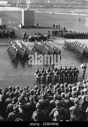 Adolf Hitler, im Mercedes stehend, (hinter ihm Wilhelm Brückner) grüßt die Formationen des Reichsarbeitsdienstes auf dem Zeppelinfeld. Im Hintergrund befindet sich das Denkmal der Arbeit, wo das Gedenken an die Toten stattfand. Im Vordergrund ist eine Gruppe von Trommlern. Stockfoto