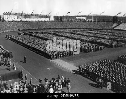 "Adolf Hitler, links auf der Rednerplattform, hält eine Rede im Stadtstadion vor den Teilnehmern des 'Tag der Hitlerjugend'. Links vom Rednerpult befindet sich der Marine-HJ. Vor ihm auf der Tartanbahn der Fotograf Heinrich Hoffmann. Auf der rechten Seite ein Kamerateam." Stockfoto