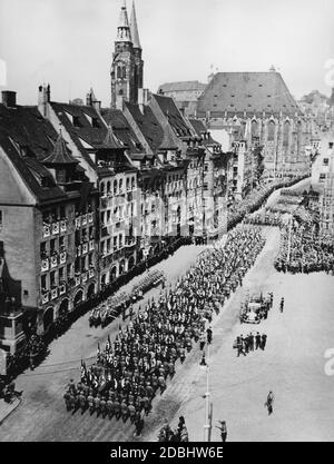 Adolf Hitler, rechts im Auto stehend, grüßt SA, SS und politische Organisationen auf dem Hauptmarkt Nürnberg, dem sogenannten Adolf Hitler Platz. Im Hintergrund die Kaiserburg, die St. Sebaldus Kirche und rechts der Schoener Brunnen. Stockfoto