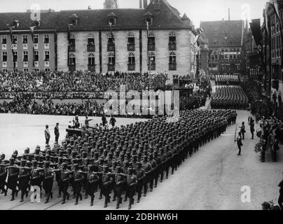 Adolf Hitler (neben ihm Rudolf Hess und Adolf Huehnlein) nimmt in einem Mercedes die Parade der NSKK-Formationen auf Nürnbergs Hauptmarkt, dem sogenannten Adolf-Hitler-Platz, in die Hand. Im Hintergrund die Tribüne. Rechts eine Musikband. Stockfoto