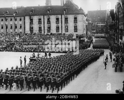 Adolf Hitler steht in einem Automobil auf dem Nürnberger Hauptmarkt und grüßt die NSKK während des NSDAP-Kongresses in Nürnberg. Auf der rechten Seite ist eine Blaskapelle und Trommler. Stockfoto