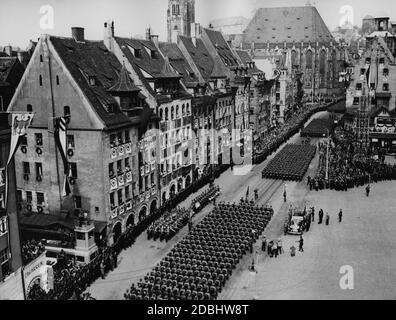 "Blick auf Nürnbergs Hauptmarkt während der Parade der Nazi-Formationen vor Adolf Hitler in seinem Mercedes (vor ihm Viktor Lutze und Rudolf Hess). Links ein Filmwagen sowie eine Blaskapelle mit einer Gruppe von Trommlern, rechts der 'Schoener Brunnen'. Im Hintergrund die Sebaldus-Kirche und auf dem Hügel die Kaiserburg.' Stockfoto