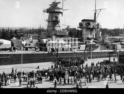 Das Panzerschiff Admiral Graf Spee in einem Hafen. Eine Menge steht vor dem Schiff und wartet, bis sie das Schiff betreten können. Stockfoto