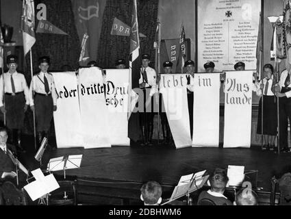 "Blick auf eine Demonstration für die Ostmark, organisiert vom Verein für das Deutschtum im Ausland am Friedrich-Wilhelm-Gymnasium in Berlin. Auf einem mehrteilig gefertigten Banner steht der Slogan ''jeder dritte Deutsche lebt im Ausland''. Im Vordergrund steht das Schulorchester. Im Hintergrund eine Gedenktafel für die Gefallenen der Einigungskriege." Stockfoto