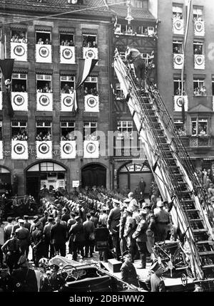 Fotograf auf einer Feuerwehrleiter während der märzvergangenheit des Reichsarbeitsdienstes auf dem Adolf-Hitler-Platz (heute: Hauptmarkt). Stockfoto