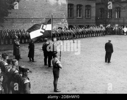 Da 92% der Schüler Mitglieder der nationalsozialistischen Jugendorganisationen sind, erhält die Oberrealschule Pankow eine Flagge der HJ. Der Schulleiter, Direktor Poppe (Zentrum in Zivilkleidung), hält eine Rede vor den Schülern, die sich auf dem Schulhof versammelt haben. Stockfoto