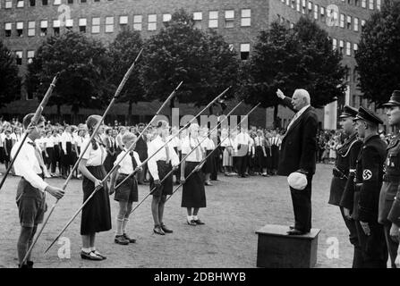 Im Sommer 1933 fand auf einem Berliner Schulhof eine Fahnenweihe für die Jugend des Volksbundes für das Deutschtum im Ausland (VDA) statt. Schüler mit 6 zusammengerollten Fahnen stehen vor einem Schulfunktionär. Stockfoto