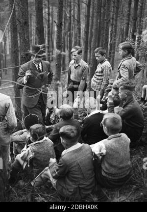 Ein Lehrer und Parteimitglied gibt seinen Schülern Anweisungen für ein Spiel auf dem Feld am Wandertag. Stockfoto