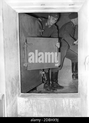 "Ein Soldat zeigt den Schließmechanismus der Eingangstür zu einem Führerbunker bei einer Pressetour durch die Air Defence Zone West im August 1939. Die Berichte über die "Westwall" (Siegfried-Linie) sollten die Angst der Bevölkerung vor einem bevorstehenden Krieg an zwei Fronten lindern." Stockfoto