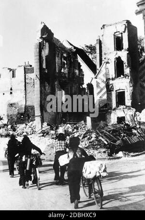 Zivilisten wandern mit Gepäck zwischen den Ruinen der zerstörten französischen Stadt Courtenay in Pay de la Loire. Stockfoto