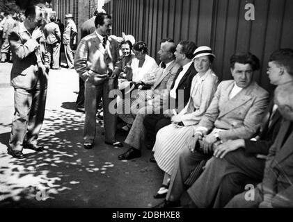 'Trubel vor dem Festspielhaus: Künstler der Bayreuther Festspiele sitzen in den Pausen auf der 'Künstlerbank' vor der Bühne.' Stockfoto