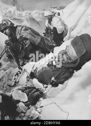 Soldaten mit einem MG 34 Maschinengewehr hinter einem gefallenen Soldaten der Roten Armee in einem Graben im Gebiet von Stalingrad. Stockfoto