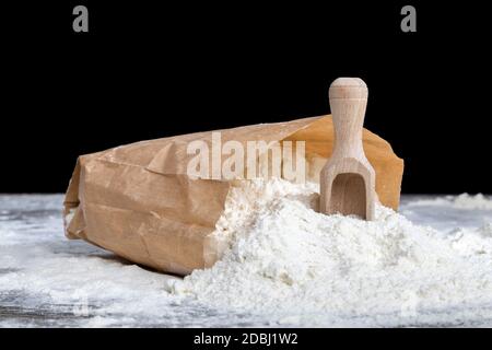 Die Zutaten für die Herstellung von Pasta aus Hartweizen, Weizenmehl in einem Papierbeutel mit einem Holzlöffel Stockfoto