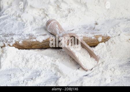 Ein einfacher Holzlöffel mit Weizenmehl beim Kochen, auf einem Küchentisch auf dem Land Stockfoto