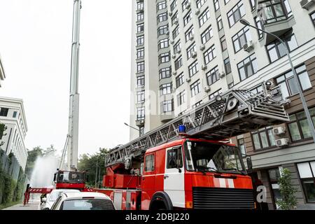 Viele Feuerwehrfahrzeuge mit Leiter und Sicherheitsausrüstung bei Unfall in Hochhaus Turm Wohnwohnung oder Bürogebäude in Stadtzentrum Stockfoto