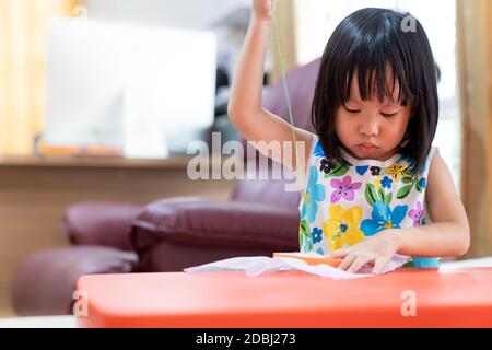 Asiatische Mädchen Kind Nähen im Wohnzimmer zu Hause als Schule zu Hause, während die Stadt gesperrt wegen der covid-19 Pandemie auf der ganzen Welt. Home Scholling vor Stockfoto