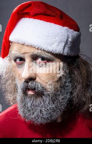 Make-up weihnachtsmann piepst aus dem Baum. halloween-Konzept weihnachten Zombie santa tot Weihnachtsmann hält Skier in den Händen und Geschenke Stockfoto