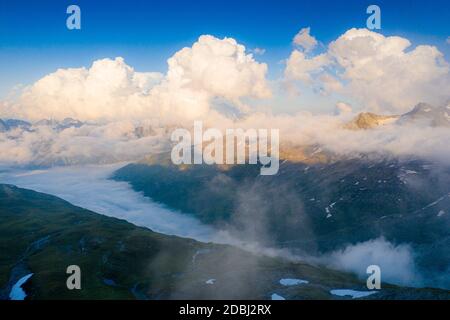 Sonnenlicht über den Bergen im Nebel, Luftaufnahme, Furkapass, Kanton Uri, Schweiz, Europa Stockfoto