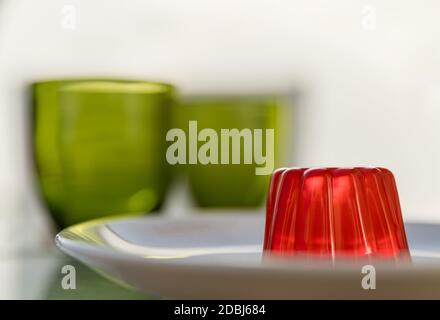 Nahaufnahme eines Erdbeergelee-Dessert mit zwei grünen Gläsern im Hintergrund Stockfoto