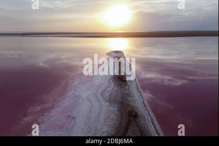 Strahlender Sonnenuntergang auf einem rosa See, orange Flare auf dem rosa Wasser des Strandes. Stockfoto