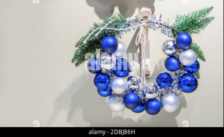 Weihnachtskranz mit dunkelblauen und weißen Weihnachtskugeln auf einer Holzhalterung. Stockfoto