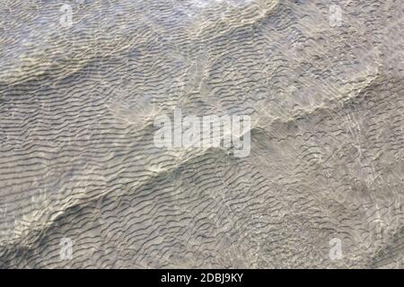 Sandstruktur unter klarem Wasser am Strand Stockfoto