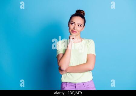 Foto von gesinnten Mädchen berühren Finger Kinn suchen leeren Raum Denken Gedanken isoliert über blauen Hintergrund Stockfoto