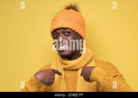 Glücklicher afrikanischer Mann, der froh ist, ausgewählt zu werden, deutet auf sich selbst hin und fragt mich, wer ich bin. Stockfoto