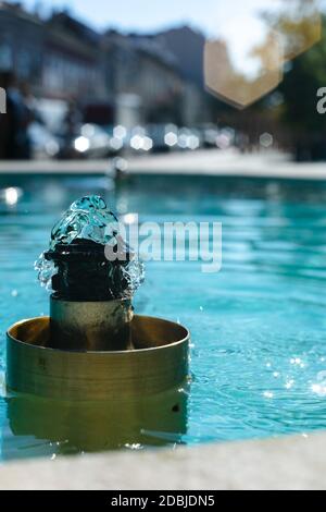 Städtischer Wasserbrunnen, der an heißen Sommertagen planscht. Stadtbild Szene von Brunnen mit türkisfarbenem Wasser Stockfoto