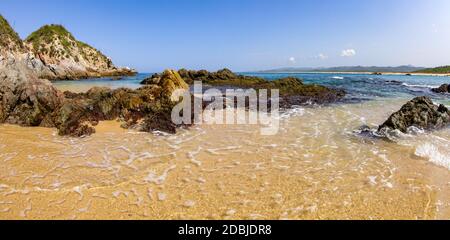 Seichtes Wasser bedeckt den Sand und die Felsen des Mayto Beach in Mexiko. Stockfoto